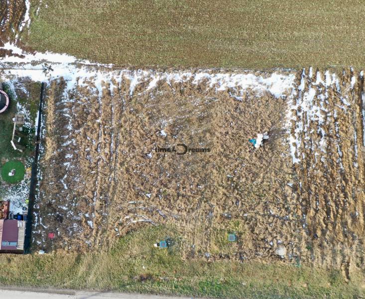 NA PREDAJ Stavebný pozemok v obci Golianovo - Letecký pohľad na pozemky pri Golianove s viditeľným snehom a vychodenými cestami.