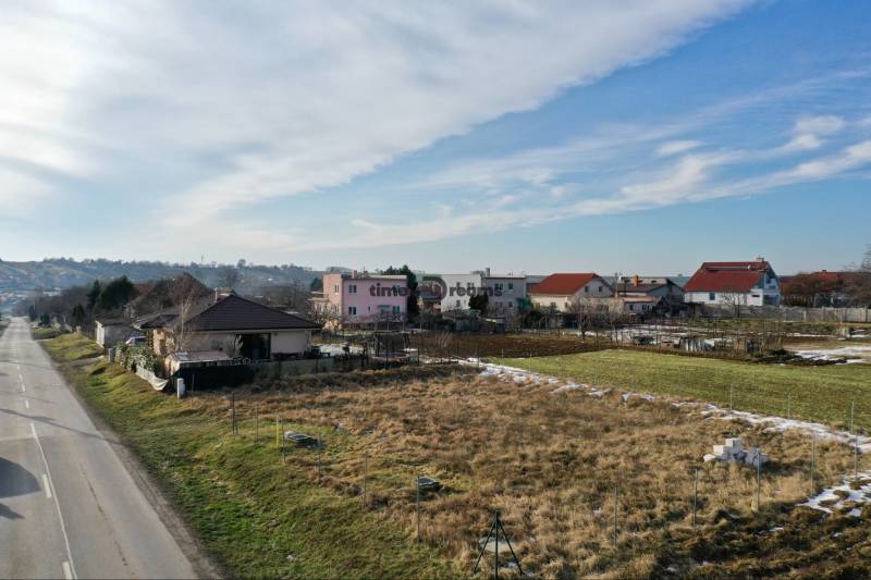 NA PREDAJ Stavebný pozemok v obci Golianovo - Pohľad na obytné pozemky v Golianove so zasneženými trávnatými plochami pri ceste.