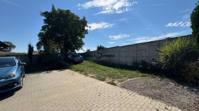NA PREDAJ Radový rodinný dom v obci Malý Lapáš - Dvor rodinného domu v Malom Lapáši so spevnenou plochou a zeleňou pri múre.