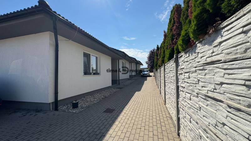 NA PREDAJ Radový rodinný dom v obci Malý Lapáš - Rodinný dom v Malom Lapáši s modernou fasádou, dlaždený chodník vedľa upraveného plotu.