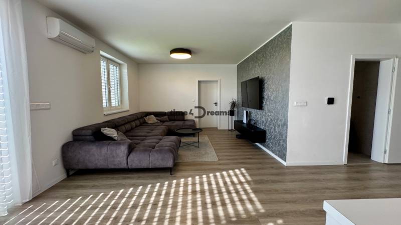 NA PREDAJ 4 izbový rodinný dom Štitáre NITRA - Obývacia izba s rohovou sedačkou, televízorom na stene a podlahou s dreveným dekorom.