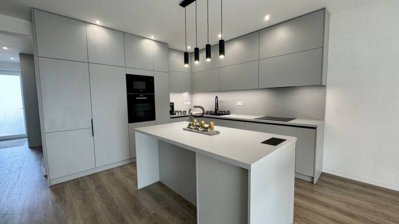 NA PREDAJ 4 izbový rodinný dom Štitáre NITRA - Kuchyňa v rodinnom dome s hladkými sivými linkami a podlahou s dreveným dekorom.