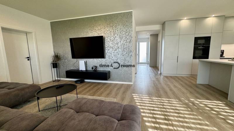 NA PREDAJ 4 izbový rodinný dom Štitáre NITRA - Obývačka v rodinnom dome s podlahou s dreveným dekorom, pohovkou a televízorom na stene.