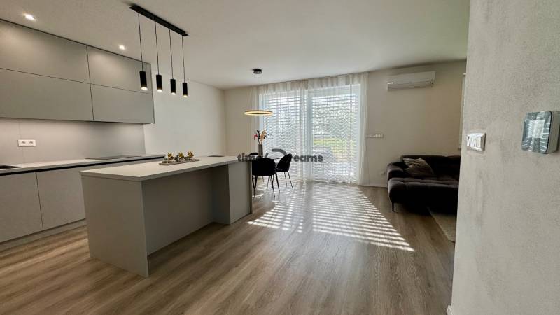 NA PREDAJ 4 izbový rodinný dom Štitáre NITRA - Kuchyňa v rodinnom dome s ostrovčekom, veľkými oknami a podlahou s dreveným dekorom.