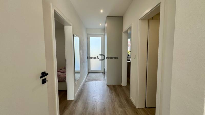 NA PREDAJ 4 izbový rodinný dom Štitáre NITRA - Chodba v rodinnom dome s podlahou s dreveným dekorom a bielymi stenami.