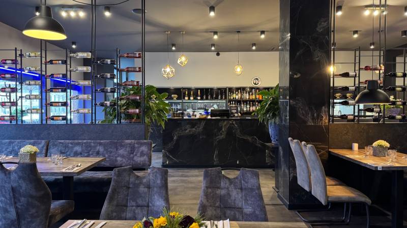 ODSTÚPENIE Gastro prevádzky na Námestí v Nitre - Gastro priestory s podlahou s dreveným dekorom, poličkami na víno a dekoratívnym osvetlením.