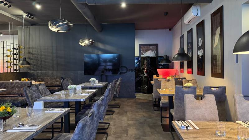 ODSTÚPENIE Gastro prevádzky na Námestí v Nitre - Interiér s podlahou s dreveným dekorom, dekoratívne lustre, elegantné sedenie v gastro priestoroch.