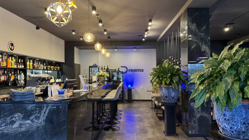 ODSTÚPENIE Gastro prevádzky na Námestí v Nitre - Gastro priestory s dlhým barovým pultom, poličkami s nápojmi a zelenými rastlinami.