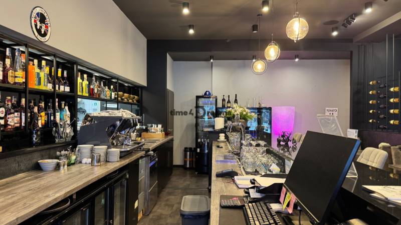 ODSTÚPENIE Gastro prevádzky na Námestí v Nitre - Barový pult v gastro priestoroch s nápojmi, kávovarom a pohármi na servírovanie.