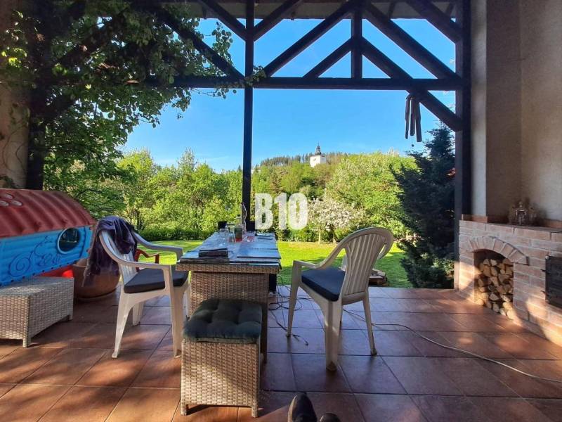 Zaujímavý rodinný dom s veľkým pozemkom, krásnou záhradou a bohatým pr - Terasa rodinného domu v Lietave s výhľadom na kostol, stôl a stoličky.