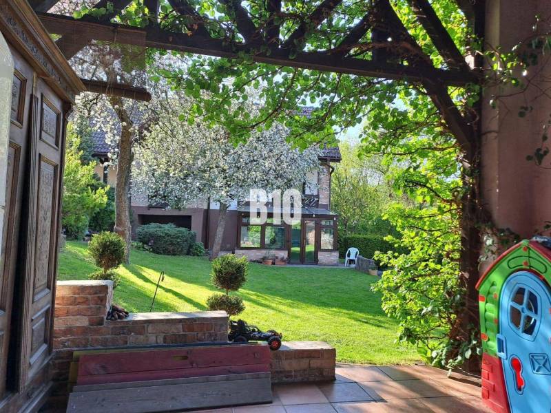 Zaujímavý rodinný dom s veľkým pozemkom, krásnou záhradou a bohatým pr - Záhrada rodinného domu v Lietave s kvitnúcimi stromami a trávnikom.