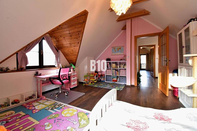 Zaujímavý rodinný dom s veľkým pozemkom, krásnou záhradou a bohatým pr - Detská izba v rodinnom dome s ružovým nábytkom a podlahou s dreveným dekorom.