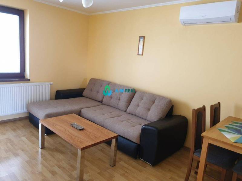 Apartmánový dom na predaj blízko termálneho kúpaliska - Obývacia izba s rohovou pohovkou, stolíkom a klimatizáciou na stene. Vhodná na ulici neuvedené.