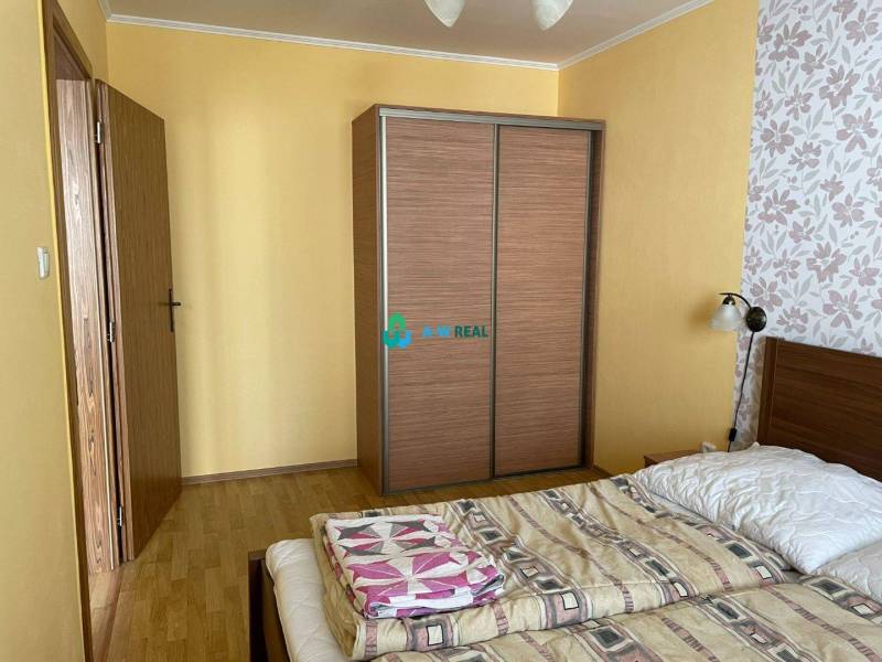 Apartmánový dom na predaj blízko termálneho kúpaliska - Spálňa v byte so žltými stenami a kvetinovou tapetou, s drevenými obchodnými priestormi.