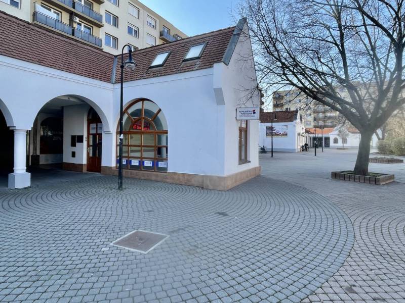 DUNASJKÁ STREDA – OBCHODNÝ PRIESTOR PRIAMO V CENTRE MESTA - Exteriér obchodných priestorov na Námestí Ármina Vámbéryho v Dunajskej Strede s dlažbou a stromom.