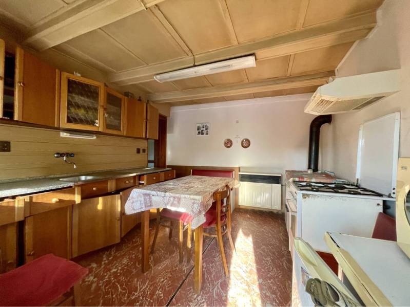 VRAKÚŇ – STARÝ RODINNÝ DOM NA PREDAJ S VEĽKÝM POZEMKOM - 24 ÁROV - Kuchyňa v rodinnom dome so sporákom, digestorom a drevenými skrinkami, podlaha s dreveným dekorom.