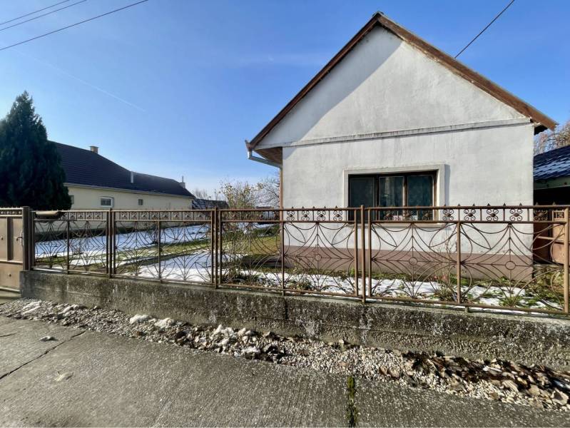 VRAKÚŇ – STARÝ RODINNÝ DOM NA PREDAJ S VEĽKÝM POZEMKOM - 24 ÁROV - Rodinný dom vo Vrakúni s bielou fasádou a kovovým plotom, mierne zasnežený dvor.