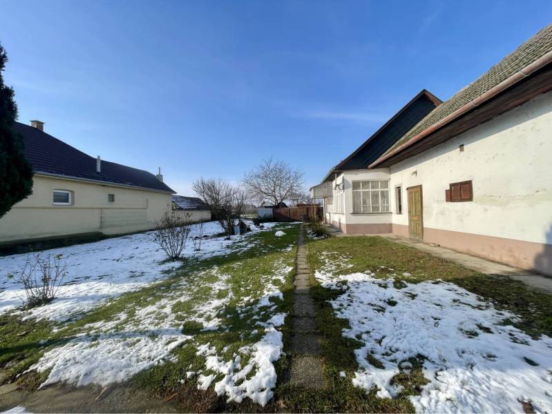 VRAKÚŇ – STARÝ RODINNÝ DOM NA PREDAJ S VEĽKÝM POZEMKOM - 24 ÁROV - Zasnežená záhrada rodinného domu vo Vrakúni. Jednoduchá architektúra na neuvedenej ulici.