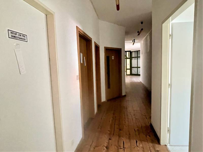Kancelárske priestory na prenájom v centre Dunajskej Stredy - Chodba v kanceláriách s dverami, podlahou s dreveným dekorom a nápisom 