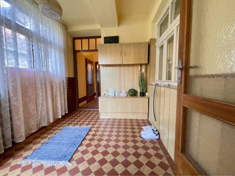 TOPOĽNÍKY – 4-IZBOVÝ RODINNÝ DOM NA PREDAJ NA 14 ÁROVOM POZEMKU - Vnútorný priestor rodinného domu, koberček, závesy, drevený nábytok, kvetinová dekorácia.