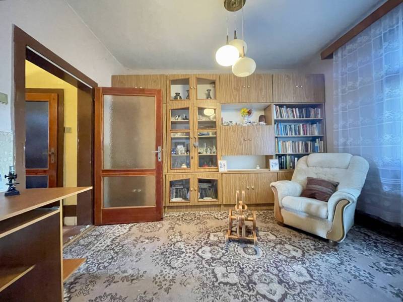 TOPOĽNÍKY – 4-IZBOVÝ RODINNÝ DOM NA PREDAJ NA 14 ÁROVOM POZEMKU - Obývacia izba v rodinnom dome s kreslom, knižnicou a sklenenými vitrínami.