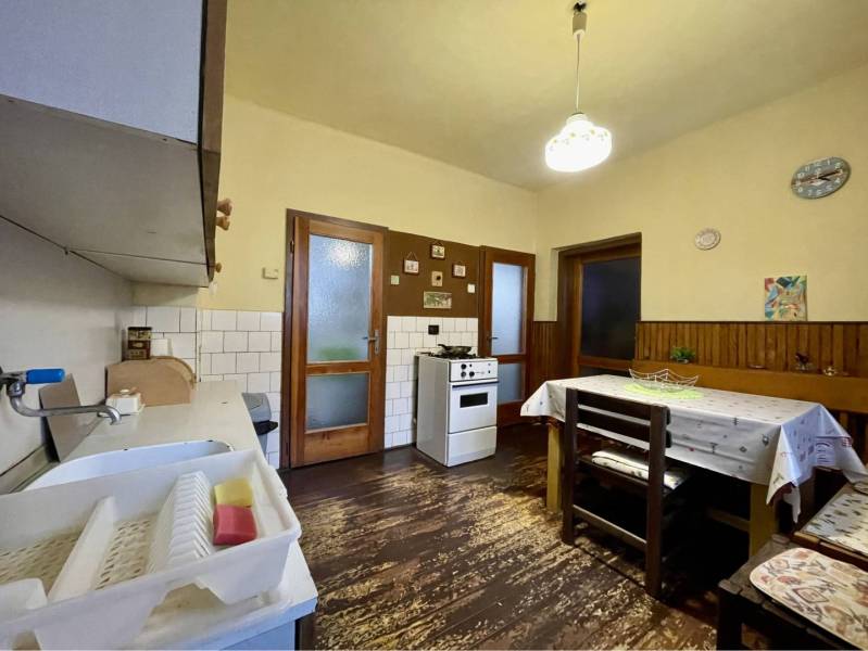 TOPOĽNÍKY – 4-IZBOVÝ RODINNÝ DOM NA PREDAJ NA 14 ÁROVOM POZEMKU - Kuchyňa v rodinnom dome s podlahou s dreveným dekorom, jedálenským stolom a plynovým sporákom.