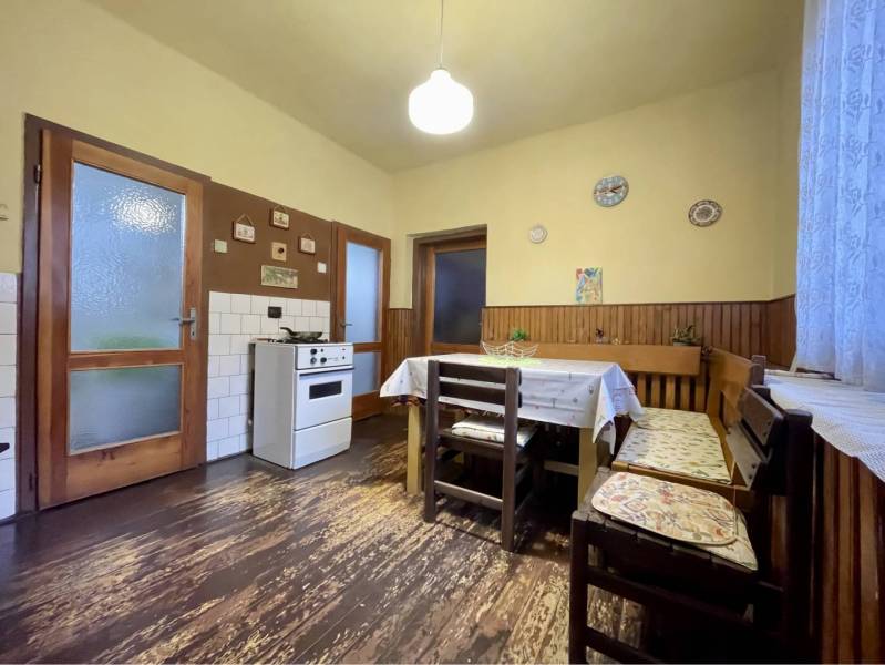 TOPOĽNÍKY – 4-IZBOVÝ RODINNÝ DOM NA PREDAJ NA 14 ÁROVOM POZEMKU - Kuchyňa v rodinnom dome s podlahou s dreveným dekorom, jedálenským stolom a sporákom.