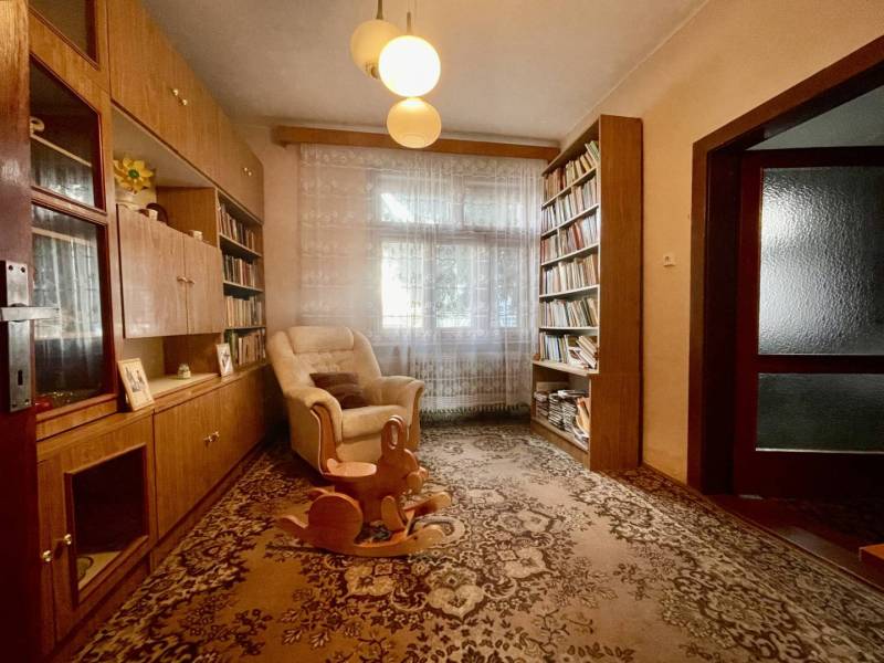 TOPOĽNÍKY – 4-IZBOVÝ RODINNÝ DOM NA PREDAJ NA 14 ÁROVOM POZEMKU - Obývacia izba rodinného domu s knihovničkou, kreslom a hojdacím koníkom.