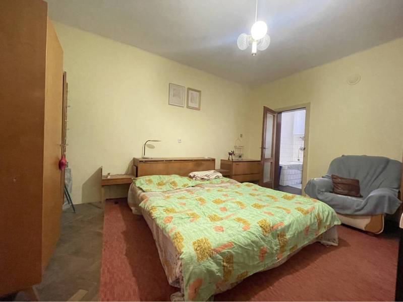 TOPOĽNÍKY – 4-IZBOVÝ RODINNÝ DOM NA PREDAJ NA 14 ÁROVOM POZEMKU - Spálňa v rodinnom dome s posteľou, skrinkami, kreslom a prístupom do kúpeľne.