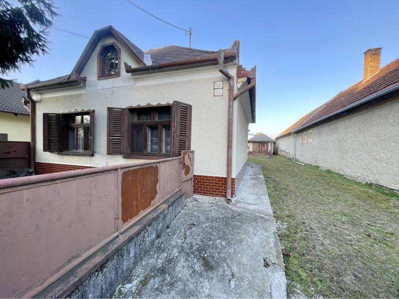 TOPOĽNÍKY – 4-IZBOVÝ RODINNÝ DOM NA PREDAJ NA 14 ÁROVOM POZEMKU - Rodinný dom na Hlavnej ulici v Topoľníkoch s drevenými okenicami a terasou.