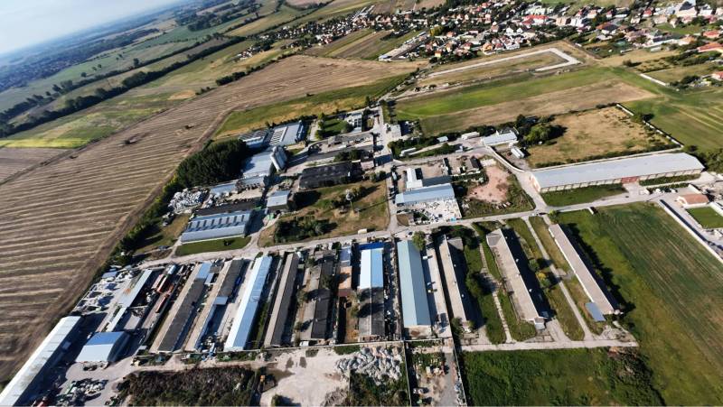 Kostolné Kračany - skladové - prevádzkové priestory na predaj za cenu  - Letecký pohľad na výrobné priestory na Amadeho Kračany v Kostolnom Kračanoch obklopené poľami.