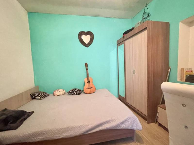 RODINNÝ DOM S ÚTULNÝM POZEMKOM NA PREDAJ V OBCI PATAŠ - Spálňa v Rodinnom dome, posteľ, zrkadlová skriňa, gitara, podlaha s dreveným dekorom.