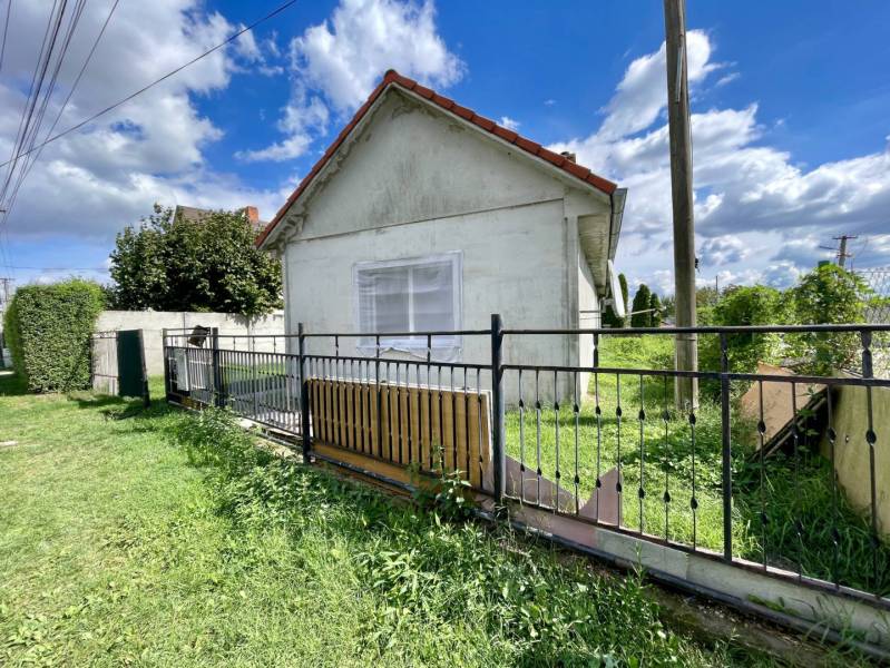 RODINNÝ DOM S ÚTULNÝM POZEMKOM NA PREDAJ V OBCI PATAŠ - Rodinný dom v Pataši s bielou fasádou, kovovým plotom a zeleným trávnikom.