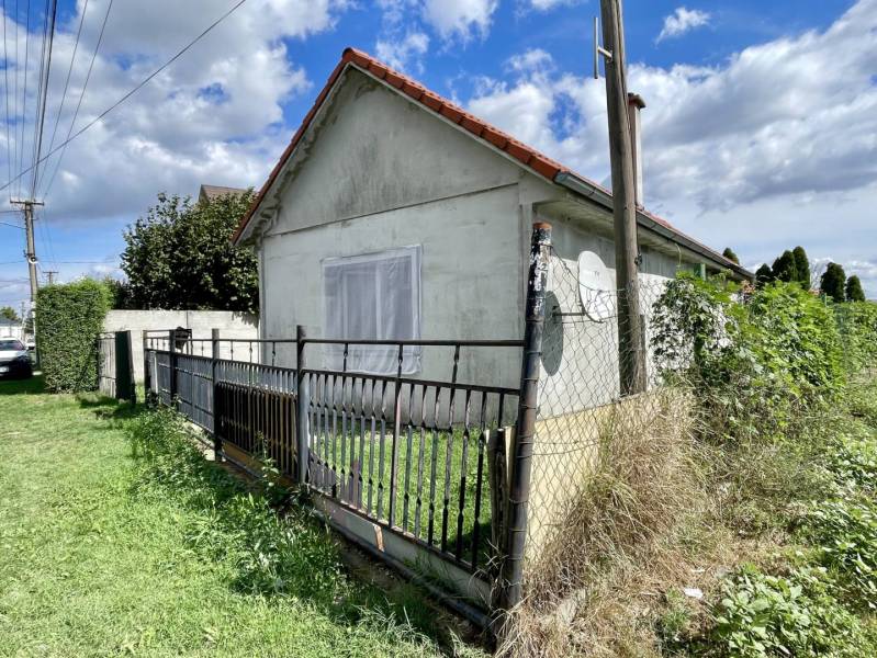 RODINNÝ DOM S ÚTULNÝM POZEMKOM NA PREDAJ V OBCI PATAŠ - Rodinný dom v Pataši s oploteným dvorom a satelitnou anténou, obklopený zeleňou.
