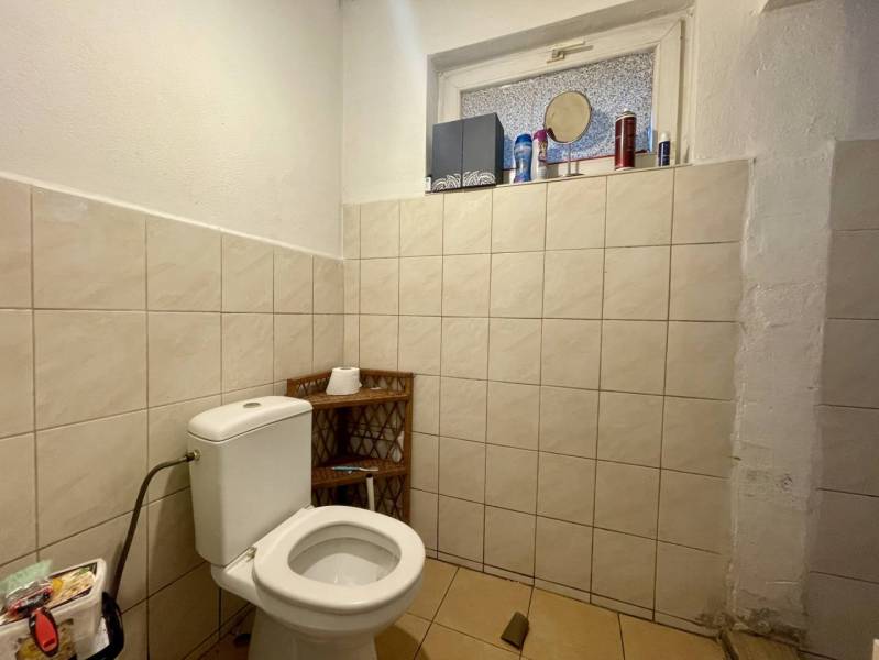 RODINNÝ DOM S ÚTULNÝM POZEMKOM NA PREDAJ V OBCI PATAŠ - Toaleta s dlaždicami a oknom v rodinnom dome, jednoduché doplnky na poličke.