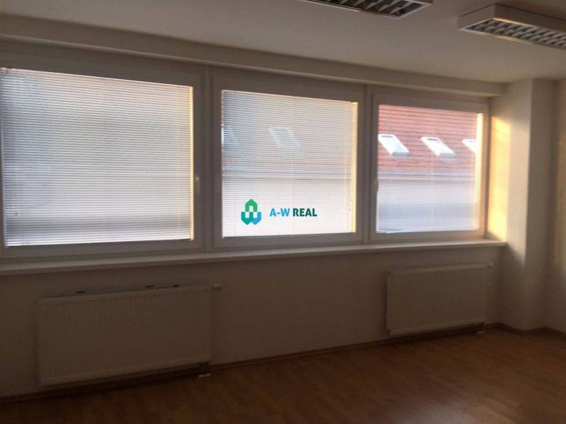 Kancelárie v centre mesta. - Priestranná kancelária s drevenou podlahou a veľkými oknami, nachádzajúca sa na ulici Hlavná.