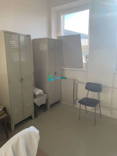 Výrobné a skladové priestory na prenájom. - Miesto na ulici Hlavná, skladovacie priestory s kovovými skriňami a stoličkou.