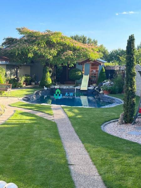 Znížená cena!  Rodinný dom s vnútorným aj vonkajším bazénom na krásne  - Rodinný dom s trávnikom, bazén so šmykľavkou, strom, chodník, plot.