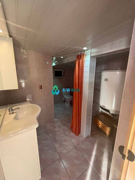 Znížená cena!  Rodinný dom s vnútorným aj vonkajším bazénom na krásne  - Kúpeľňa s umývadlom, kotlom a oranžovým závesom vytvára funkčný priestor v rodinnom dome.