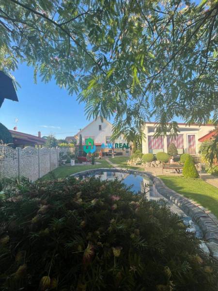 Znížená cena!  Rodinný dom s vnútorným aj vonkajším bazénom na krásne  - Záhrada rodinného domu s jazierkom na ulici neuvedene, obklopená zeleňou a kvetmi.