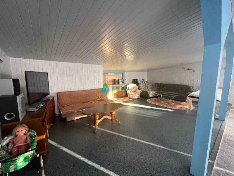 Znížená cena!  Rodinný dom s vnútorným aj vonkajším bazénom na krásne  - Na obrázku je obývačka v rodinnom dome s pohovkami a detským kočíkom.