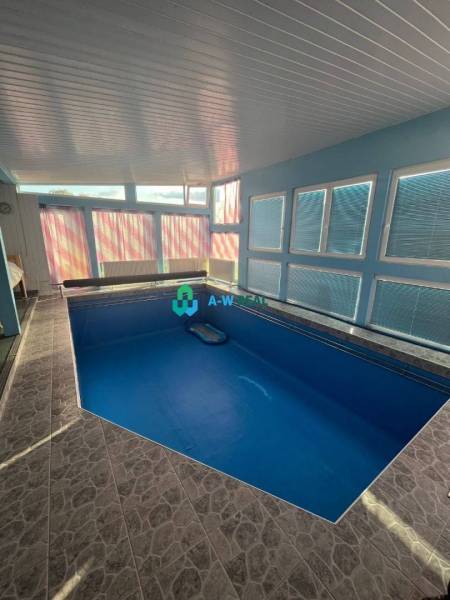 Znížená cena!  Rodinný dom s vnútorným aj vonkajším bazénom na krásne  - Rodinný dom má krytý bazén s modrými stenami a veľkými oknami na ulici neuvedene.