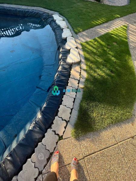 Znížená cena!  Rodinný dom s vnútorným aj vonkajším bazénom na krásne  - Záhrada s bazénom, dlažbou a trávnikom pri rodinnom dome na ulici neuvedene.