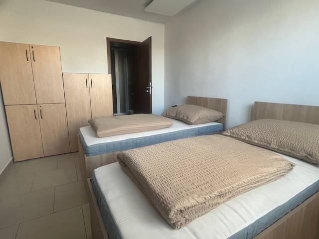 Apartmány na prenájom. - Spálňa s dvomi posteľami a skriňou v bledých odtieňoch v útulnej budove.