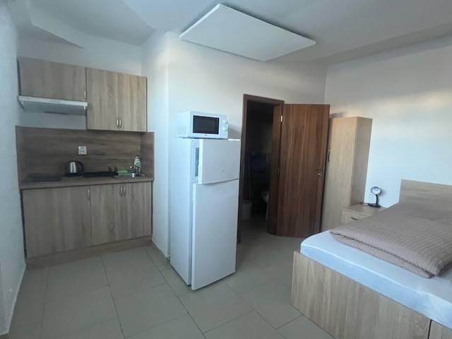 Apartmány na prenájom. - Kuchyňa a spálňa, malý byt, drevený nábytok, posteľ a skriňa integrujú funkcionalitu.