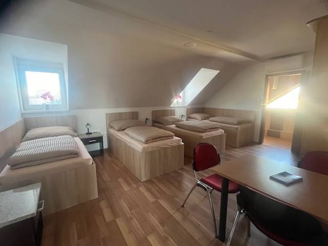 Apartmány na prenájom. - Izba so štyrmi posteľami, stolom a svetlými drevenými podlahami. Penzión ponúka ubytovanie.