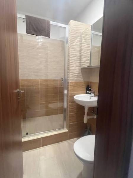 Apartmány na prenájom. - Malá kúpeľňa so sprchovým kútom, umývadlom a toaletou, obkladačky a drevené dvere.