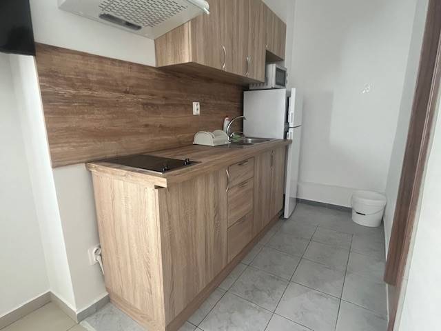 Apartmány na prenájom. - Kuchyňa s drevenou kuchynskou linkou, keramickou doskou a bielou chladničkou, Budova.