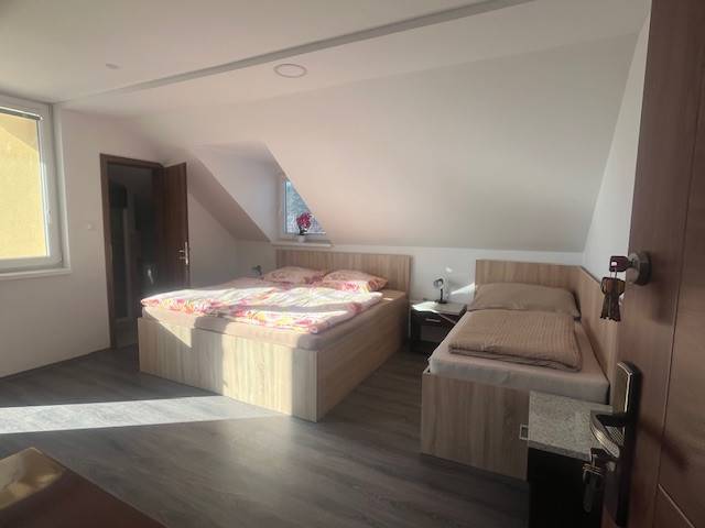 Apartmány na prenájom. - Spálňa s dvoma posteľami a oknom v podkrovnej budove.