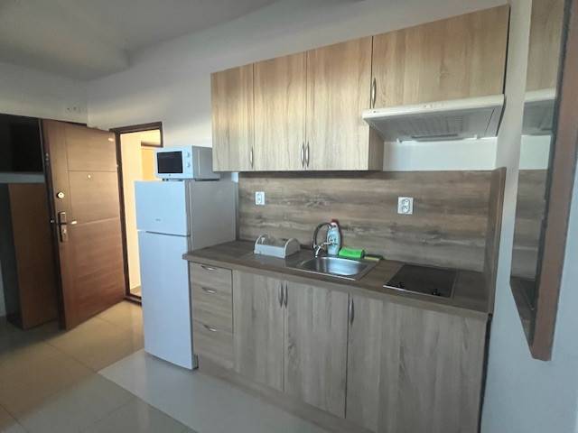 Apartmány na prenájom. - Kuchynská linka so spotrebičmi, drevené skrinky, drez, chladnička a varná doska v interiéri budovy.